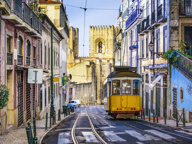 A street scene of a yellow tram trundling through Lisbon, Portugal